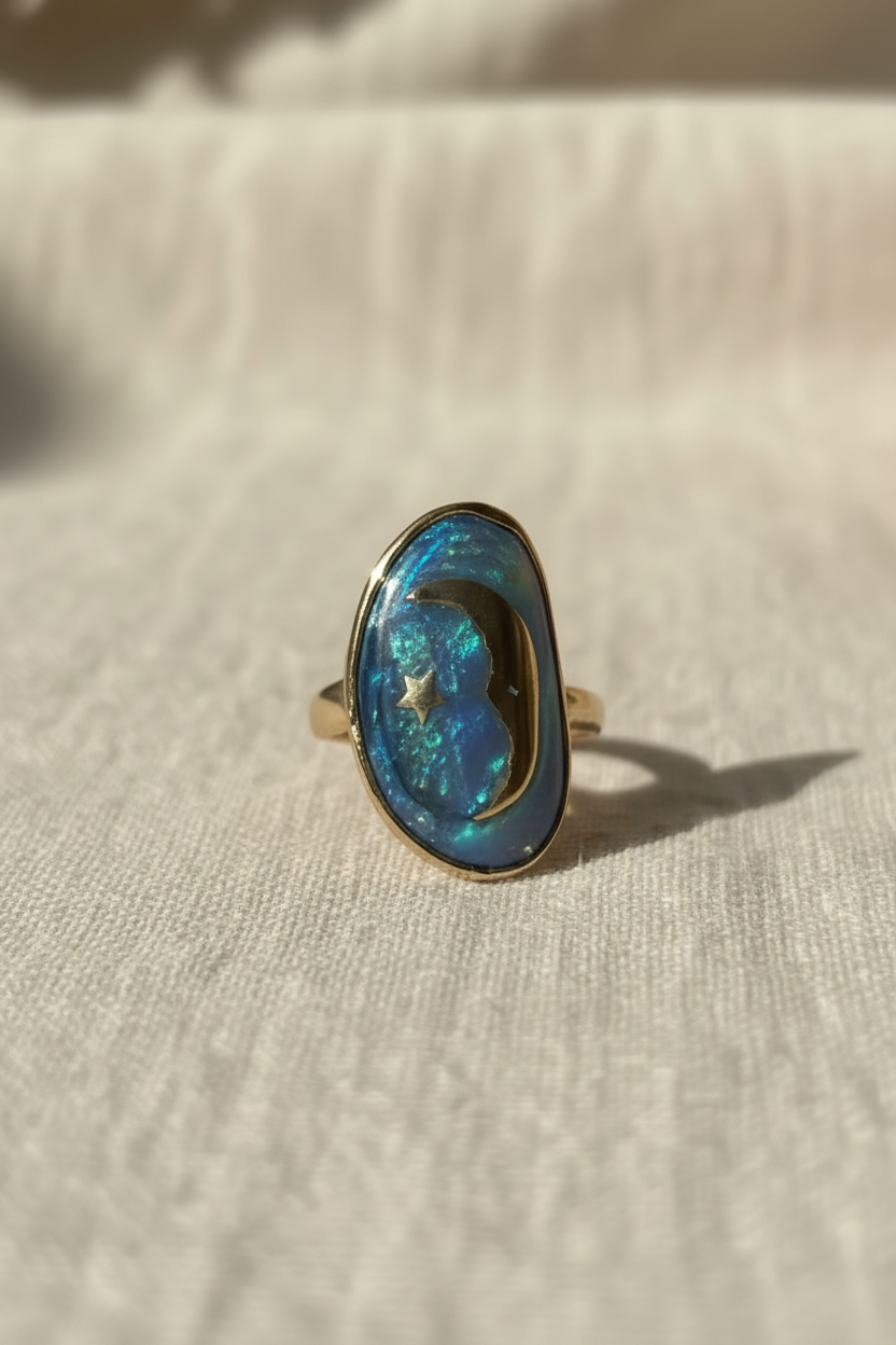 Détail de la bague Luna en laiton doré à l'or fin avec pierre bleue irisée et motif lune et étoile.