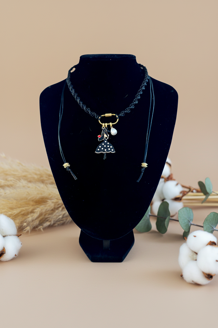 Bijou créateur Joyas by Jo : collier médaillon poupée et perle, présenté sur buste noir avec décorations de coton naturel.