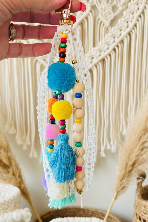 Bijou de sac pompons multicolores et perles bois tenu en main décor macramé - accessoire bohème Joyas by Jo
