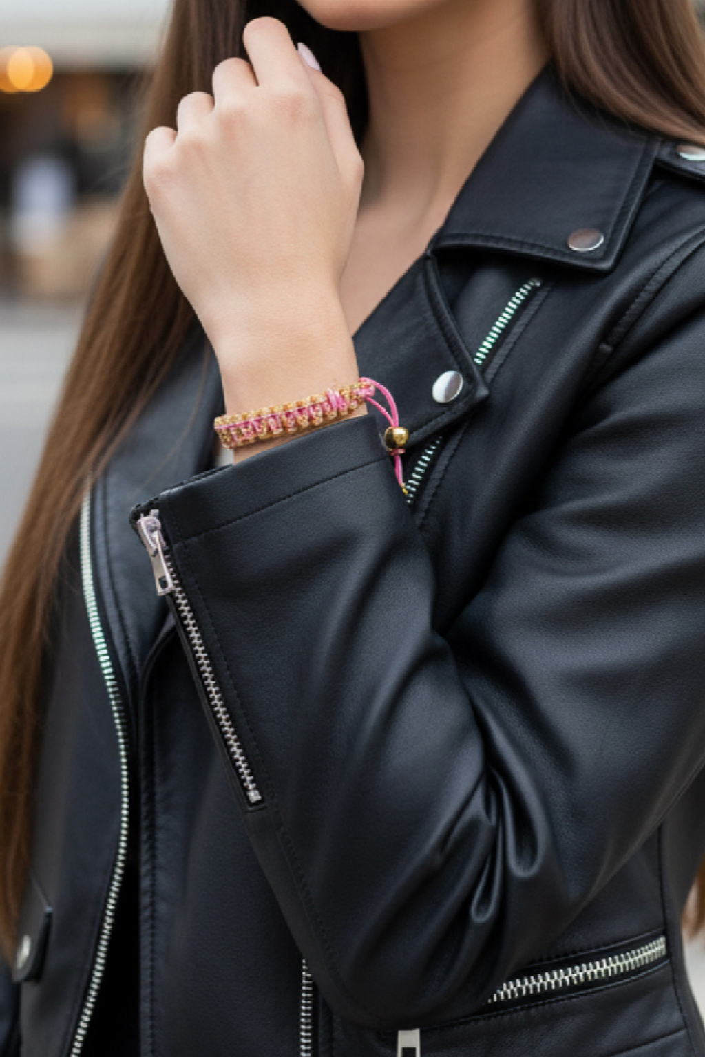 Bracelet tressé Joyas by Jo rose et doré porté avec un blouson en cuir noir pour un style rock chic.