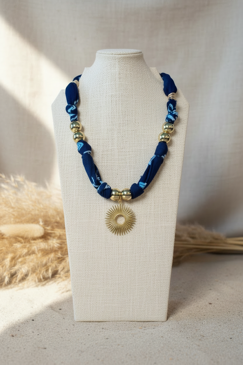 Collier Mareen "Rayon de Nuit" présenté sur un buste, composé d'un cordon bleu nuit épais orné de détails dorés et d'un large pendentif circulaire ciselé en or. Joyas by jo
