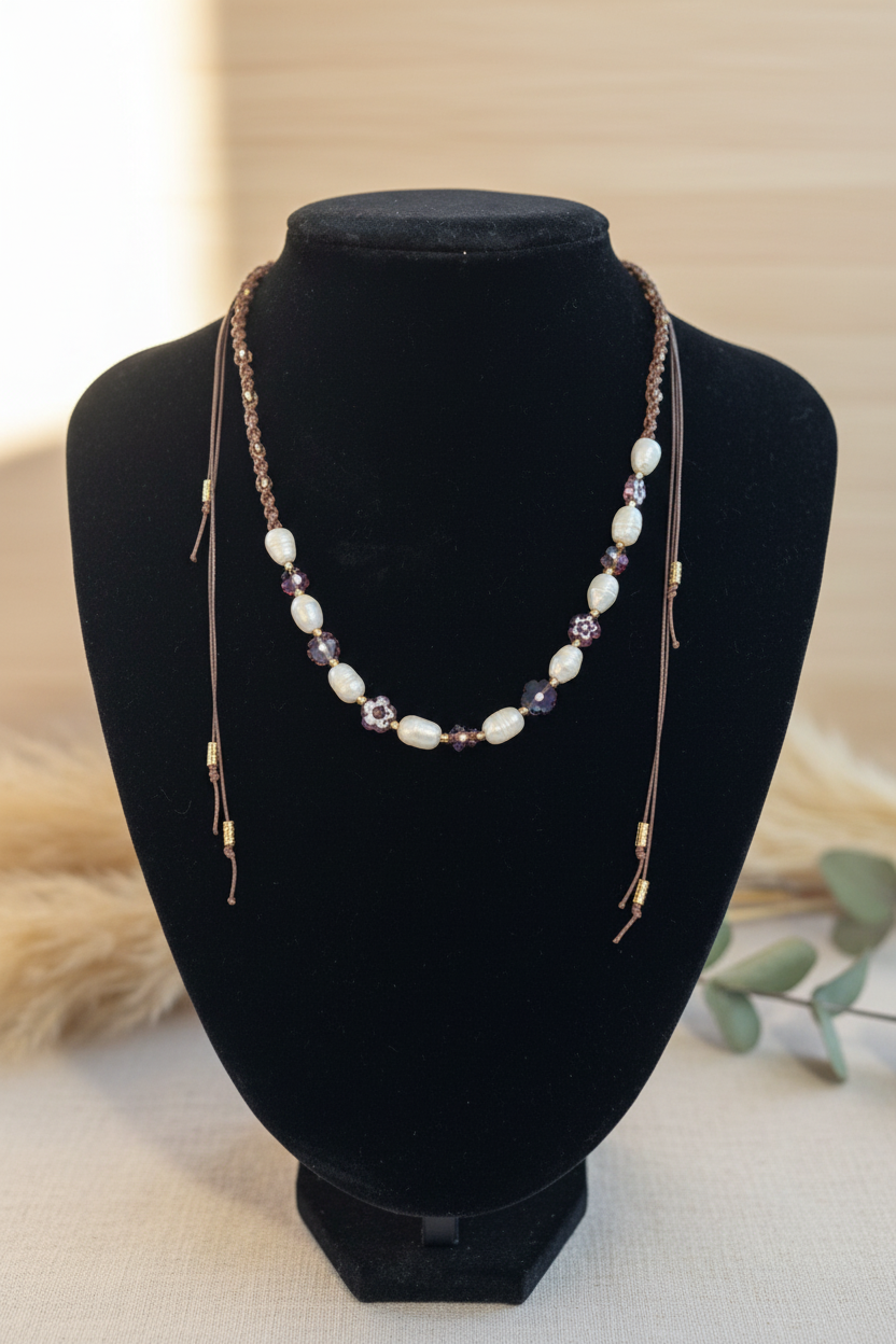 Collier artisanal Joyas by Jo en macramé marron orné de perles de nacre blanches et de perles de verre marron sur un buste de présentation.