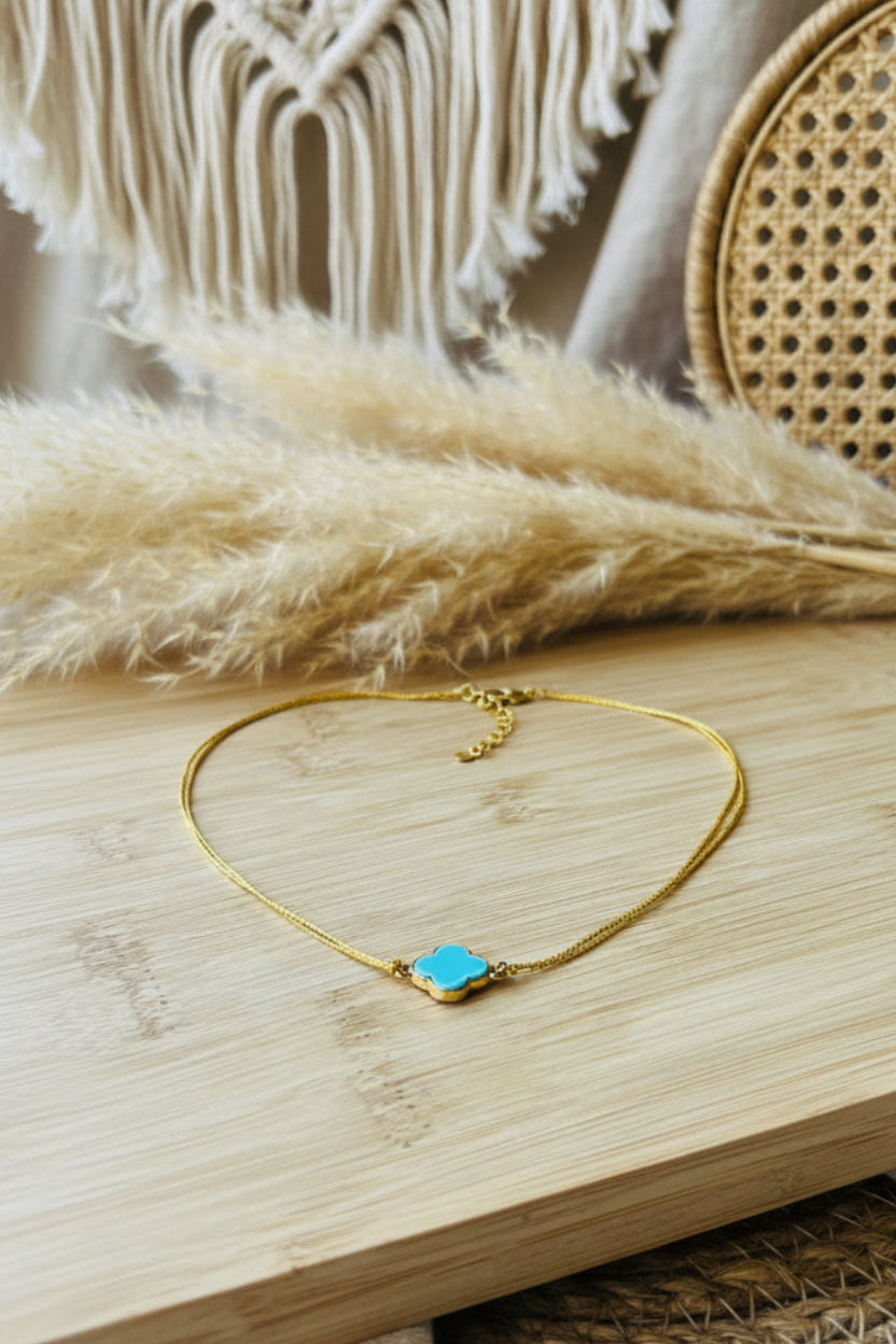 Collier fin en fil doré résistant avec pendentif trèfle bleu turquoise.