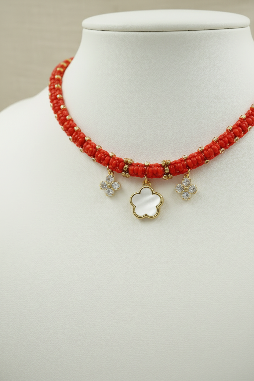 Détails des finitions du collier Joyas by Jo : cordon rouge artisanal, pendentif fleur en nacre et détails dorés.