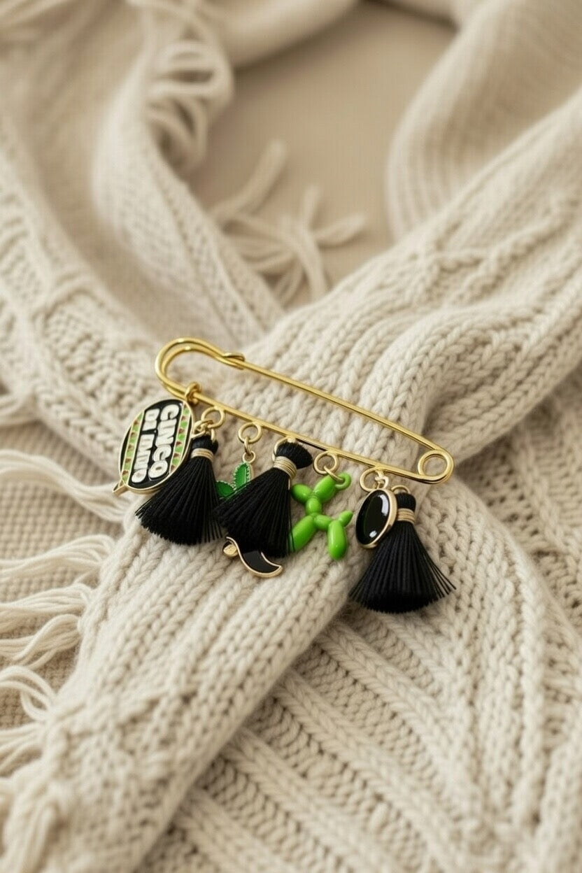 Sac à main artisanal en crochet beige avec bijou de sac amovible. Épingle dorée à breloques noires et vertes pour une personnalisation élégante et moderne d'accessoires faits-main.