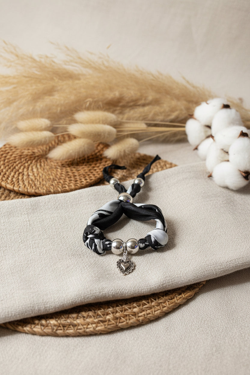 Gros plan du bracelet en tissu Joyas by Jo avec pendentif coeur sacré entouré de fleurs de coton et pampa.