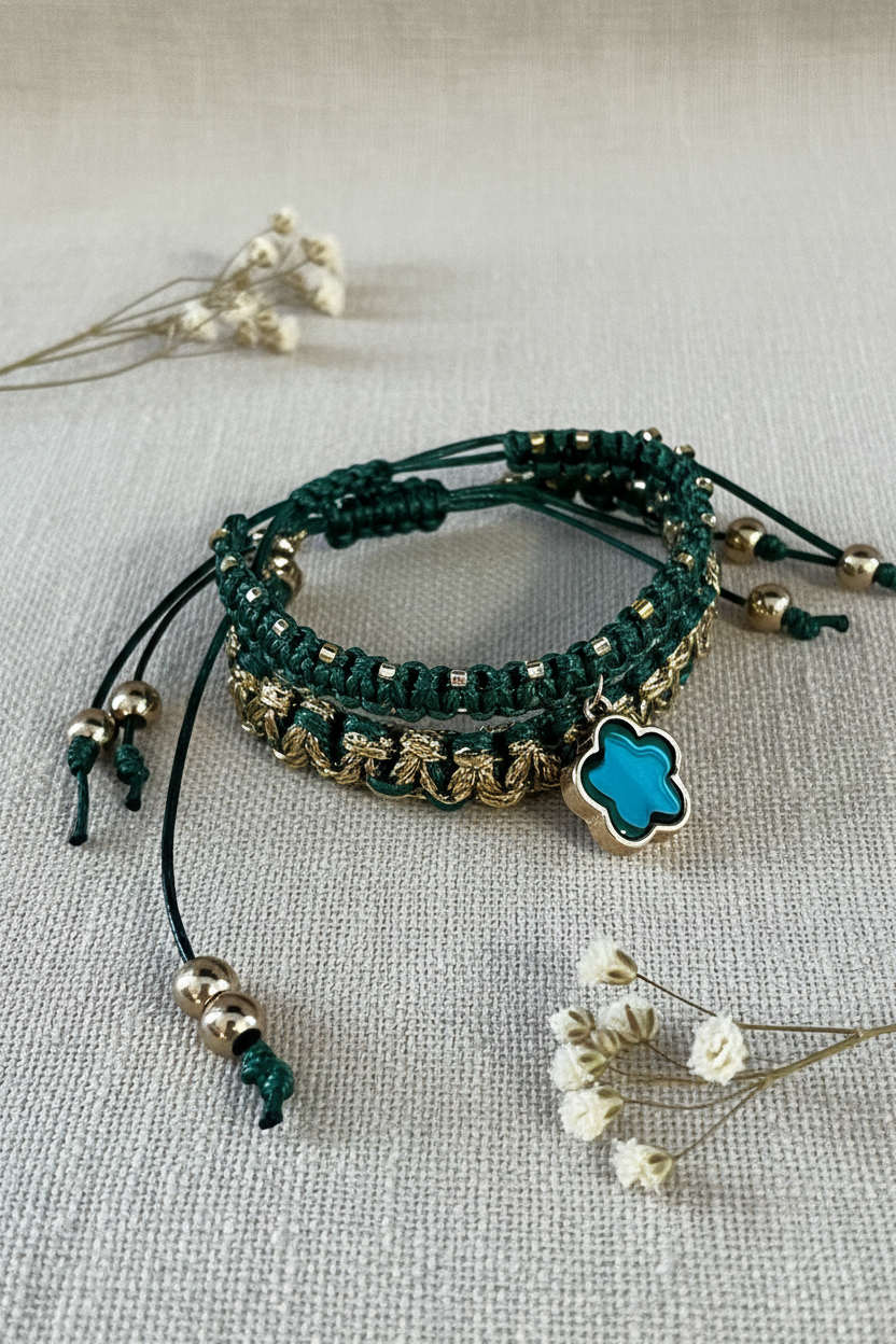 Bracelets Joyas by Jo en macramé vert émeraude et doré avec charm trèfle bleu turquoise sur fond lin.