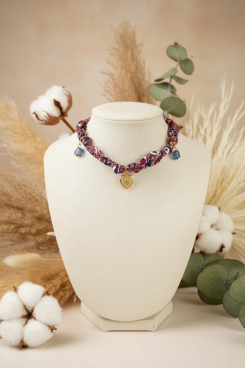 Collier artisanal Joyas by Jo en tissu bordeaux et bleu sur buste d'exposition avec fleurs de coton.