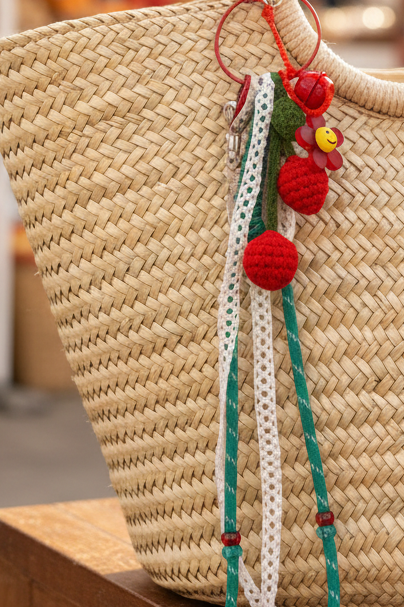 Porte-clés cerise au crochet avec fleur smiley sur sac beige plage - accessoire bohème luxe Joyas by Jo
