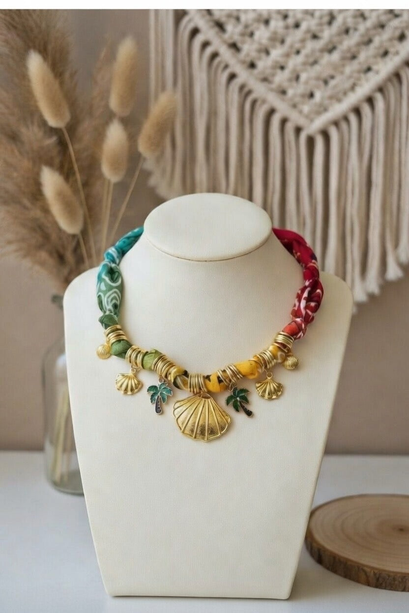 Gros plan du collier Joyas by Jo sur un buste blanc présentant le travail du tissu torsadé et les détails des breloques marines.